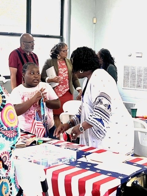 Cynthia Johnson talking with a young volunteer at a red, white and blue campaign table